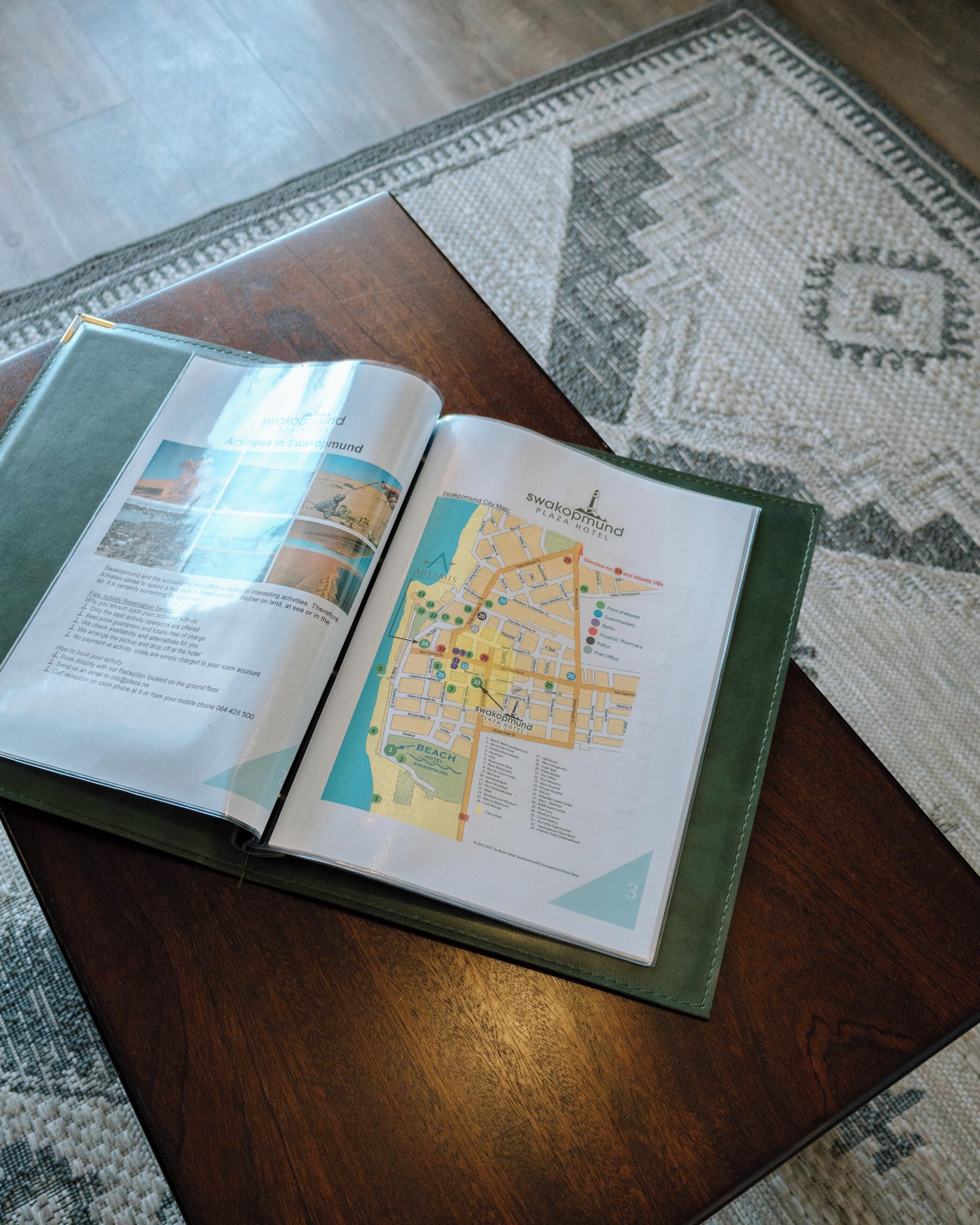 An open brochure with a map and text, placed on a wooden table.