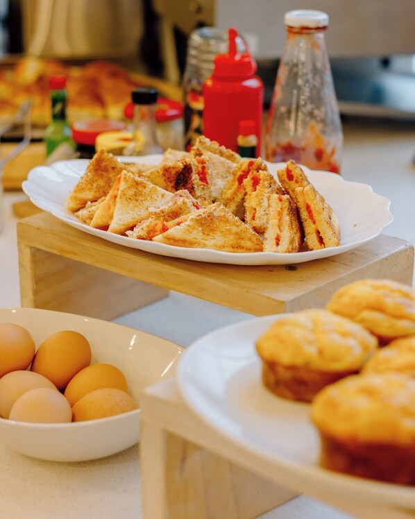 Un bufé de desayuno con diversas opciones de comida, incluyendo huevos, muffins y sándwiches.