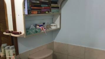 Une salle de bain avec des toilettes, un lavabo et des étagères au-dessus des toilettes.