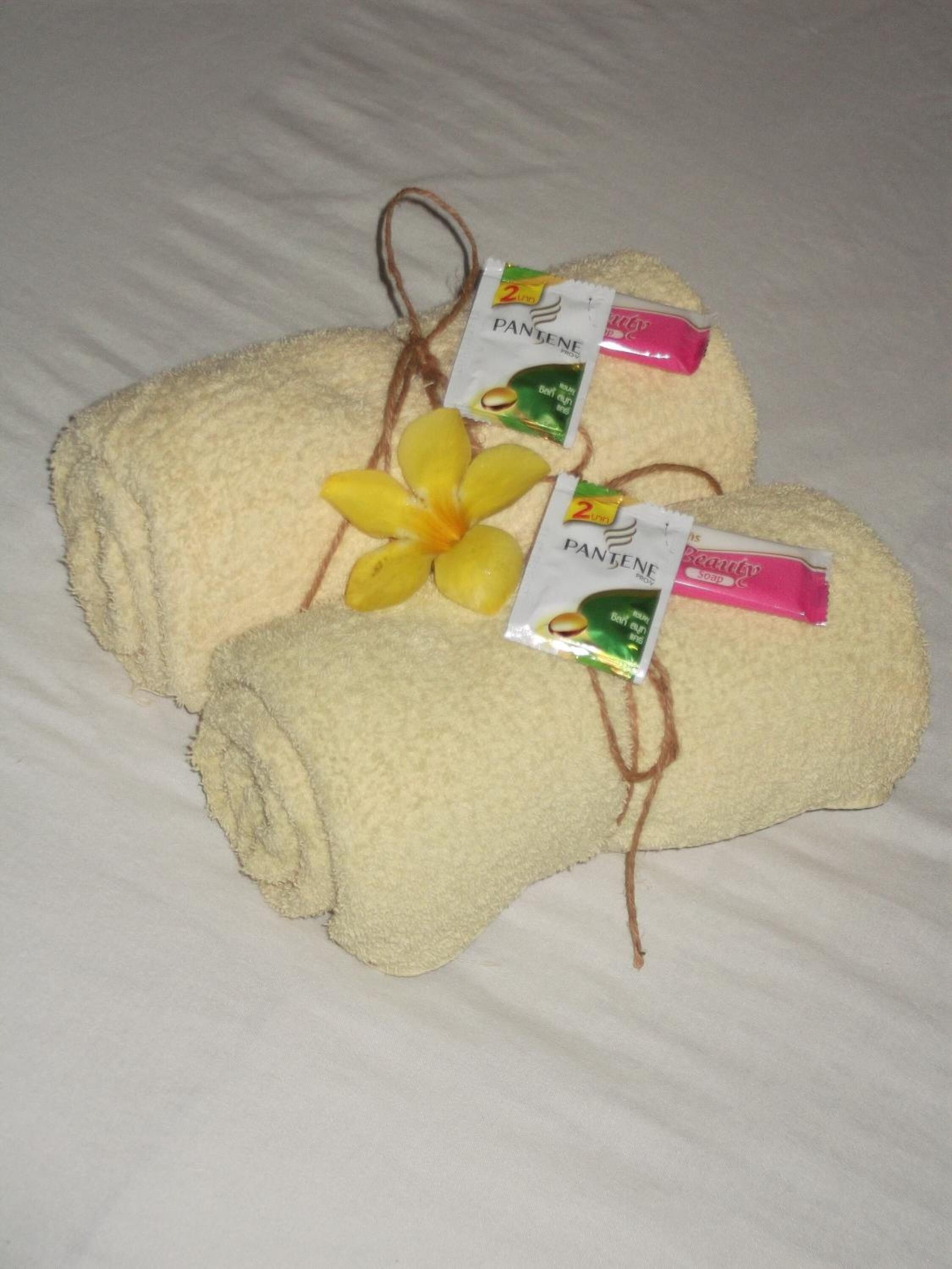 Duas toalhas com produtos Pantene e uma flor sobre a cama.