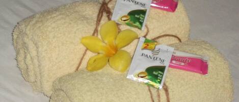 Duas toalhas com produtos Pantene e uma flor sobre a cama.