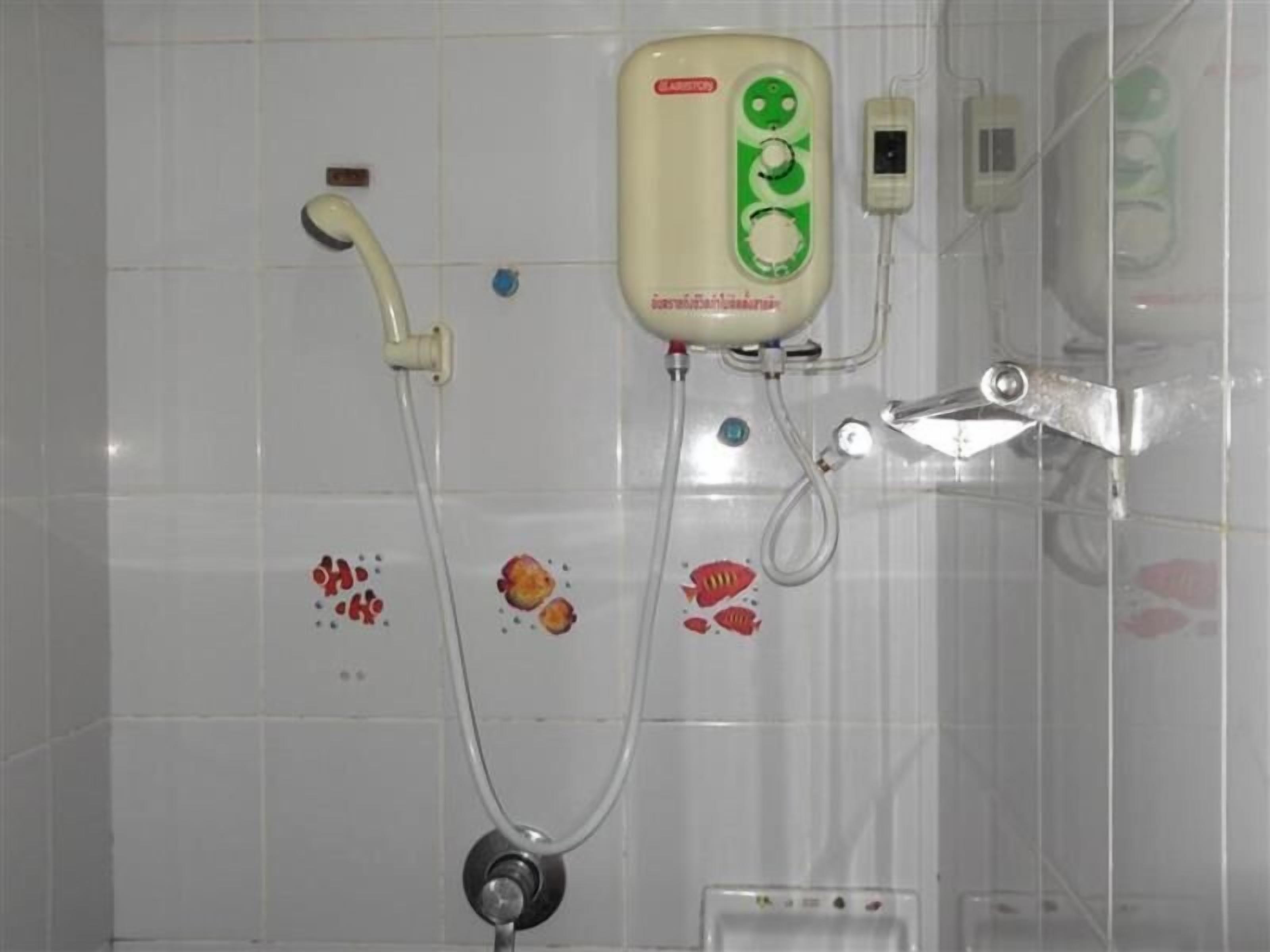 A bathroom with a shower, a handheld showerhead, and a wall-mounted control panel.