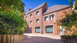 A red brick building with multiple windows and a paved courtyard. - Hotel Infotel (Mons)
