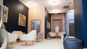 A modern interior with a seating area featuring sofas and a table, a decorative sculpture, and artwork on the walls. - Hotel d'Alcantara (Tournai)