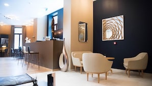 A modern hotel lobby with a reception desk, seating area, and artwork on the walls. - Hotel d'Alcantara (Tournai)