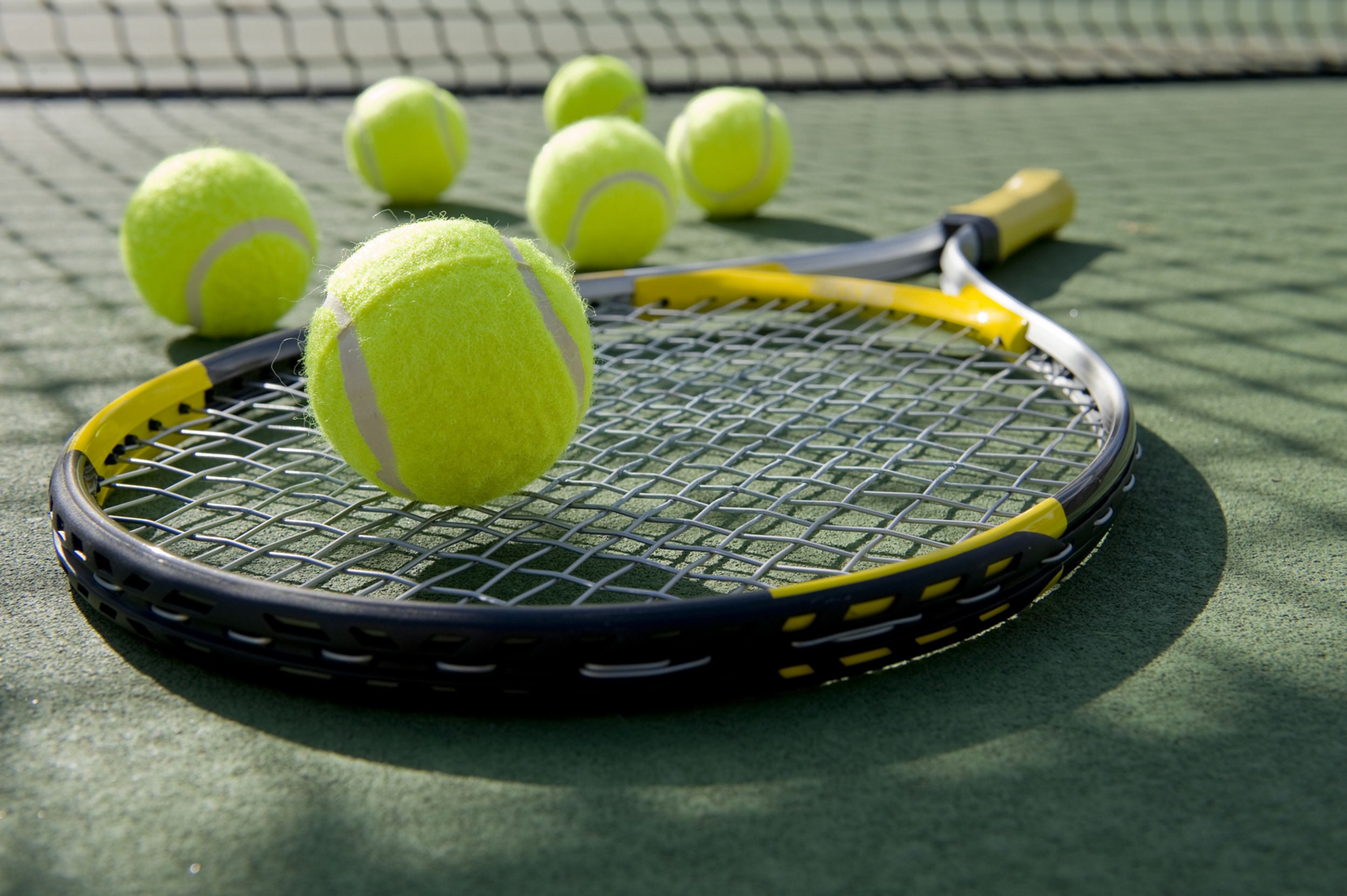 A tennis racket and balls on a green surface.