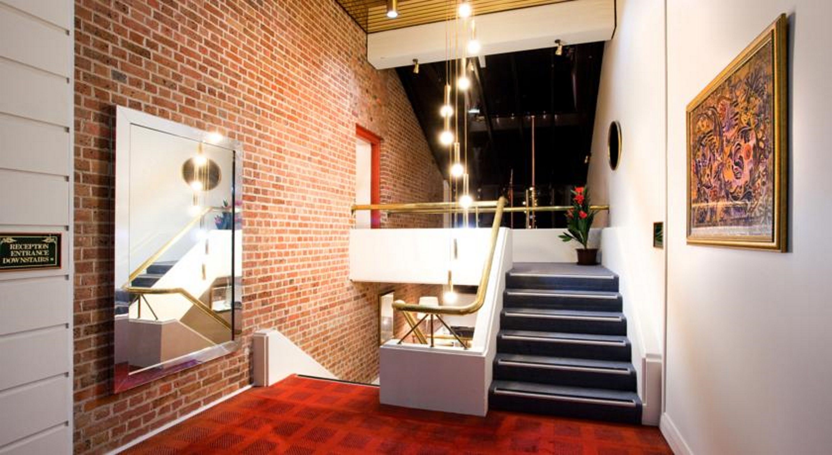 A reception area with a brick wall, a staircase, and a framed artwork on the wall.
