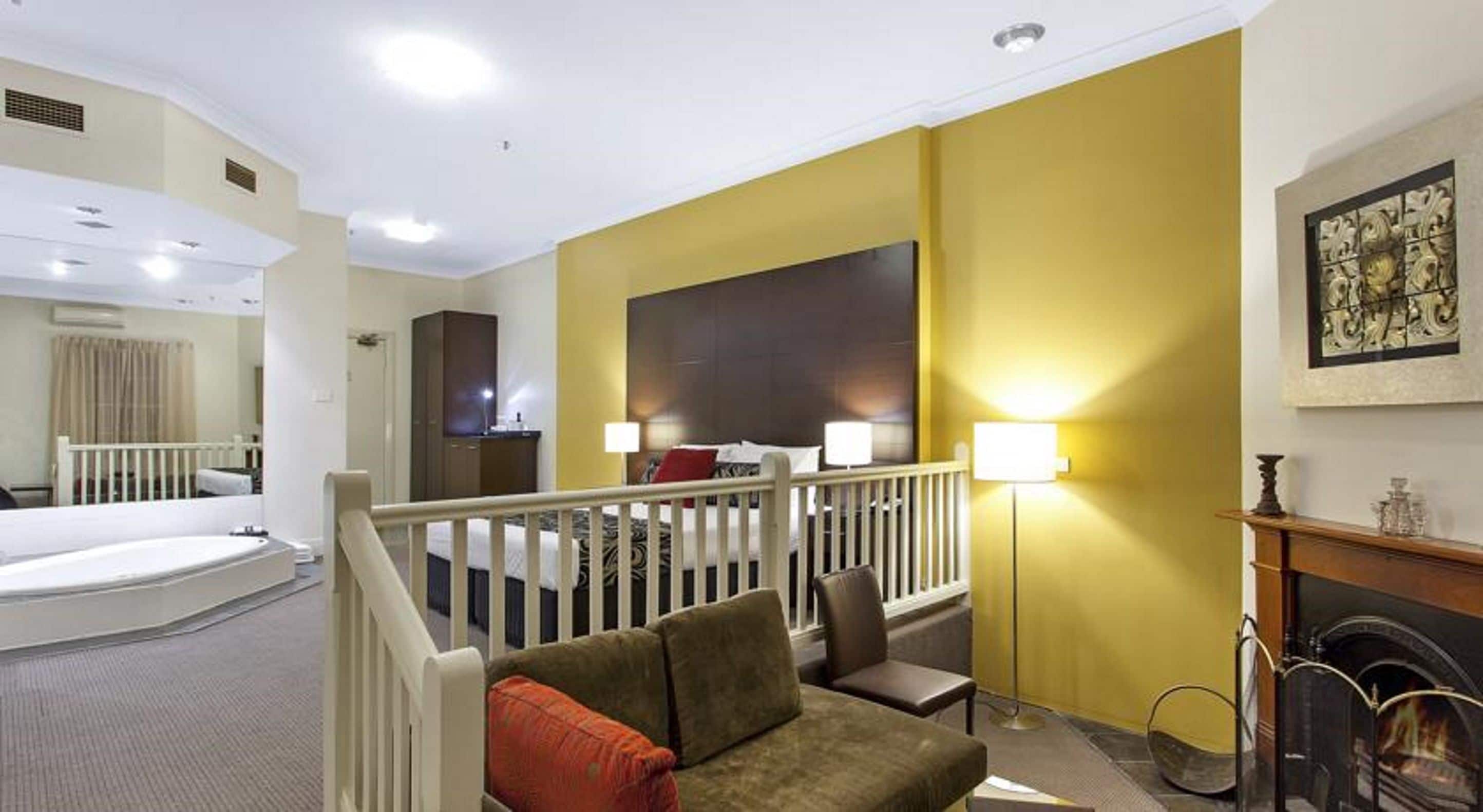 Una habitación de hotel con balcón, chimenea, sofá y cama.