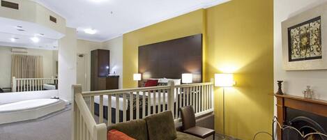 Una habitación de hotel con balcón, chimenea, sofá y cama.