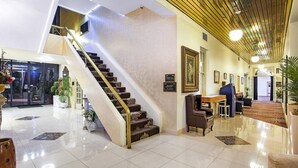 A spacious lobby with a grand staircase, a reception desk, and a seating area. - Mercure Maitland Monte Pio (Maitland)