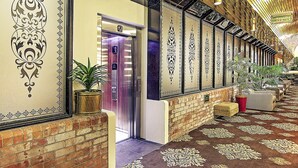 A hallway with a patterned carpet, brick walls, and decorative wall panels. - Mercure Maitland Monte Pio (Maitland)