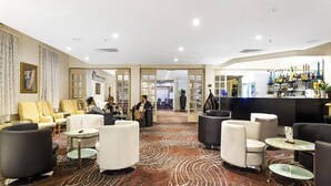 A spacious lobby with a patterned carpet, seating areas, and a bar with bottles. - Mercure Maitland Monte Pio (Maitland)