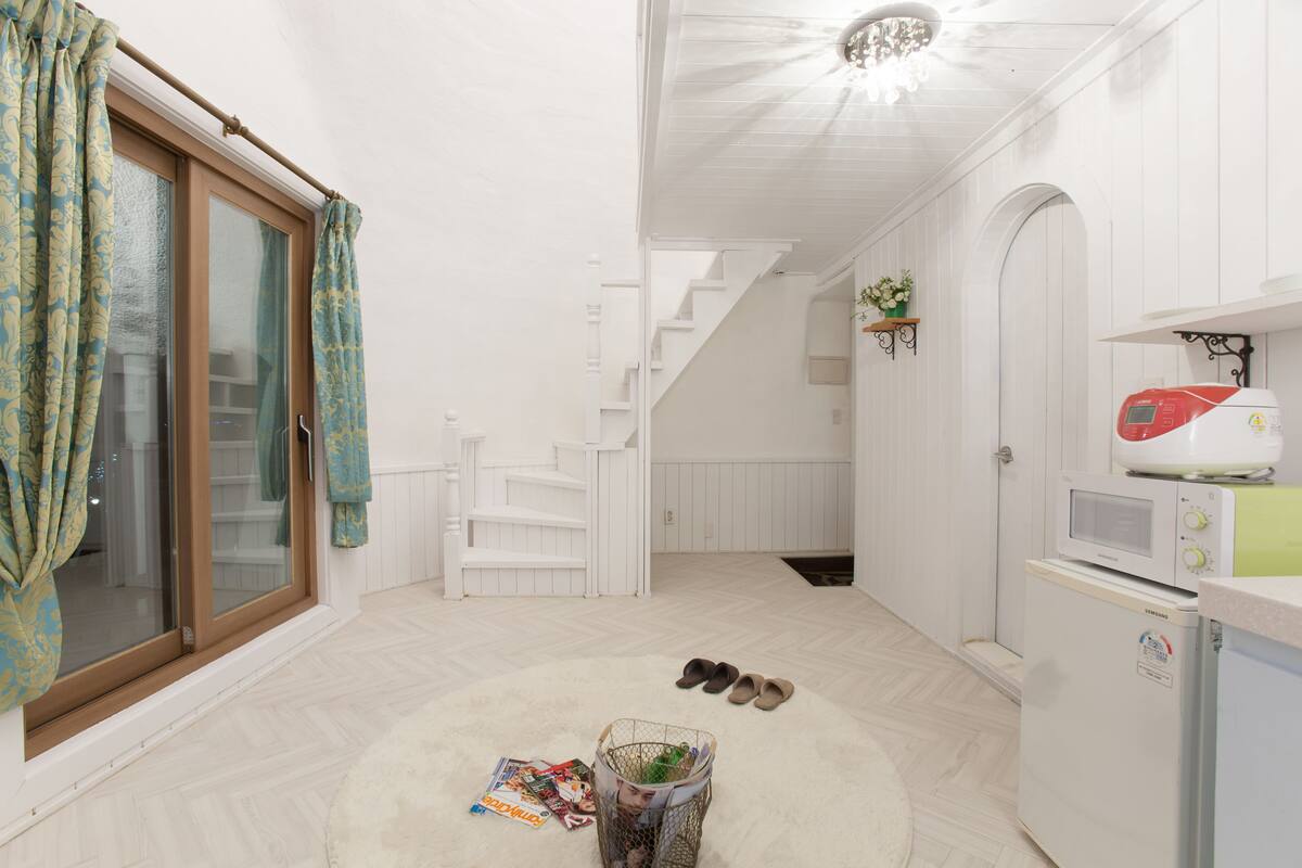 A clean, white interior with a kitchen area, a staircase, and a dining area.