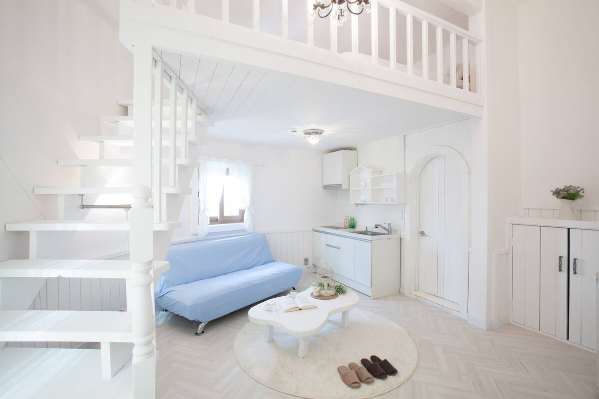 A bright, white interior with a loft bedroom, a kitchen, and a living area.