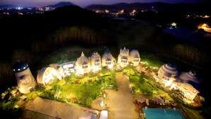 Un resort con diversi edifici a forma di cupola, una piscina centrale e vialetti ben illuminati.