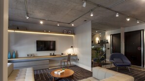 Uma sala de estar moderna com um sofá, mesa de centro e uma TV de tela plana fixada na parede.