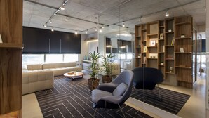 Uma sala de estar moderna com um sofá seccional, uma poltrona cinza, uma mesa de centro e uma estante.