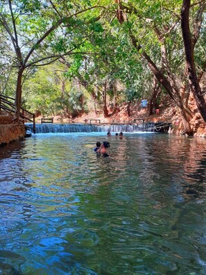 A natural pool with a waterfall, surrounded by trees and rocky terrain. - Prime Águas da Serra (Rio Quente)