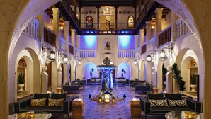 A spacious lobby with a central fountain, multiple seating areas, and a balcony overlooking the lobby. - The Villa Casa Casuarina (Miami Beach)