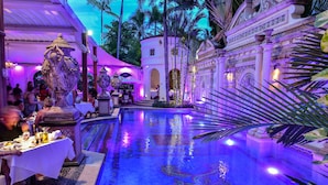 A pool area with a fountain, tables, and a tropical garden setting. - The Villa Casa Casuarina (Miami Beach)