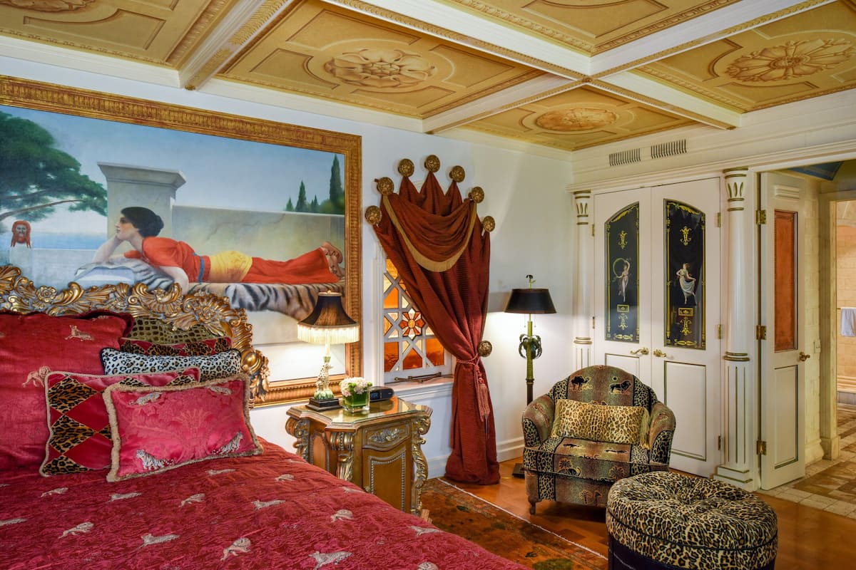 Una habitación lujosa con una cama grande, muebles ornamentados y un cuadro en la pared.