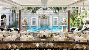 A luxurious outdoor dining area with a pool, elegant chairs, and a decorative fountain. - The Villa Casa Casuarina (Miami Beach)