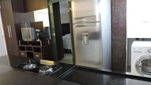Uma cozinha moderna com frigorífico de aço inoxidável, máquina de lavar embutida e fogão a gás.
