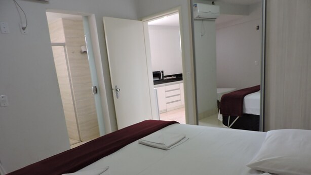 Quarto de hotel com cama, banheiro e cozinha compacta.