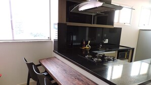 Cozinha compacta com ilha central, fogão a gás e micro-ondas.