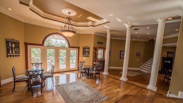 A spacious living room with hardwood flooring, a large dining table, and a chandelier.