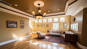A spacious living room with hardwood floors, a chandelier, and multiple framed pictures on the walls.