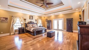 A spacious bedroom with a large bed, a ceiling fan, and a wooden floor.