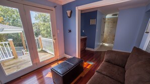 A living room with a wooden floor, a brown couch, and a black ottoman.