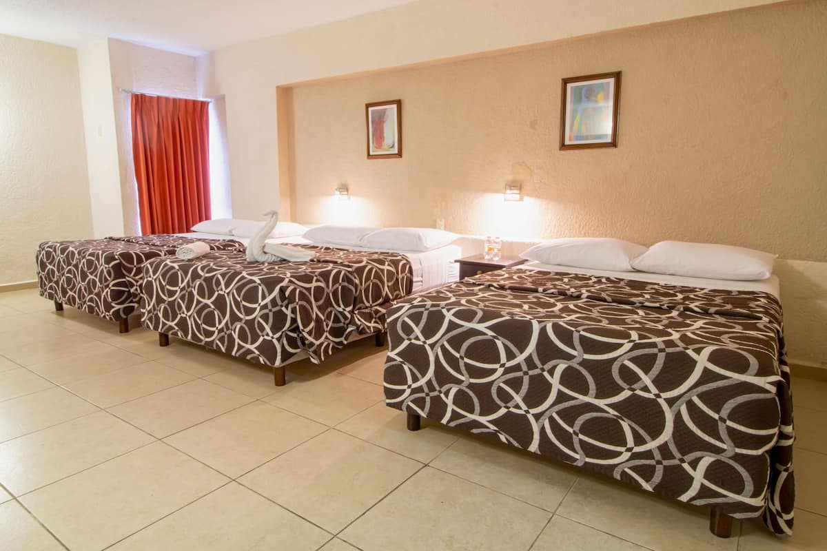 A hotel room with three beds, each with patterned bedding, a red curtain, and two wall-mounted lights.