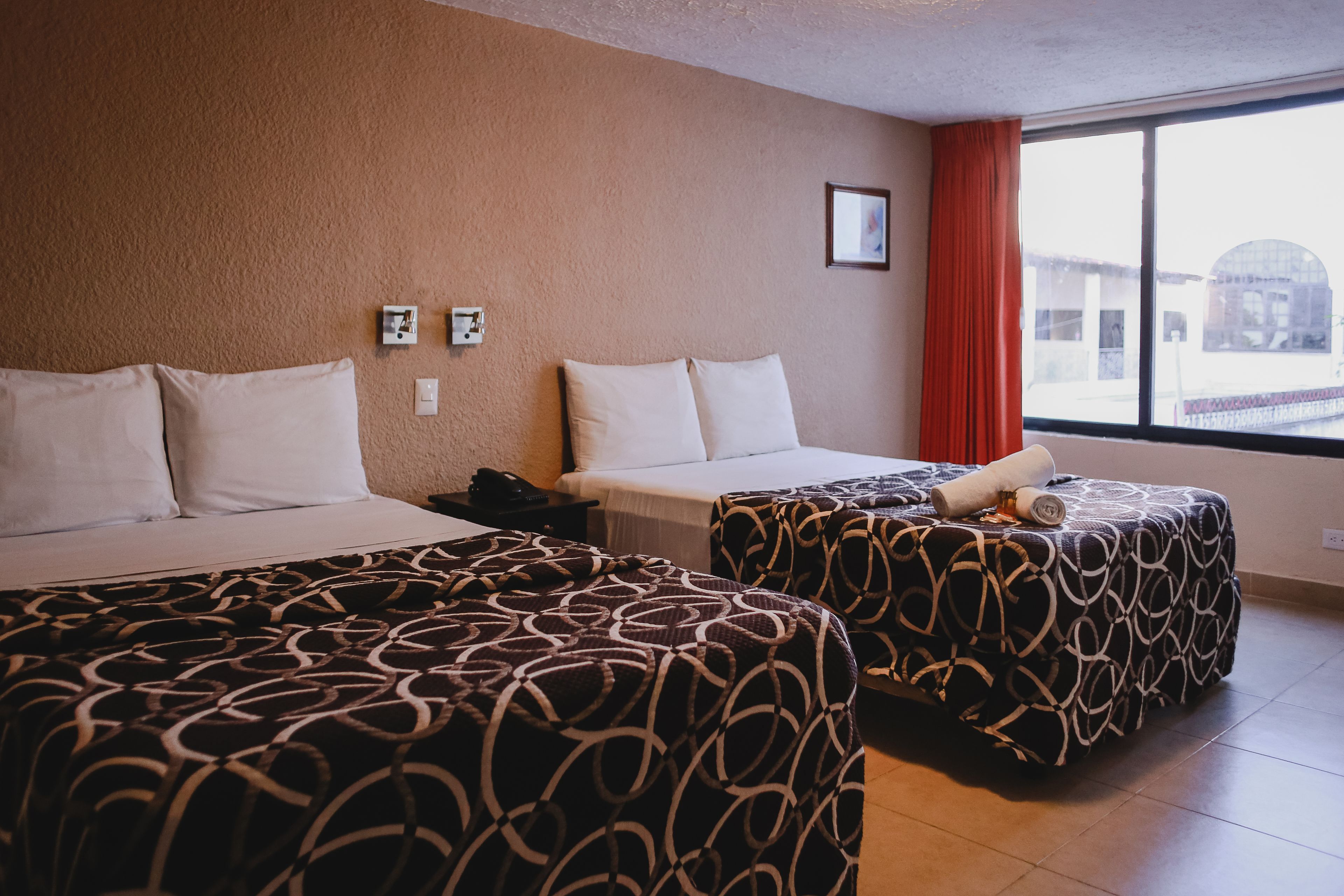 Ein Hotelzimmer mit zwei Betten, einem großen Fenster und Blick nach draußen.