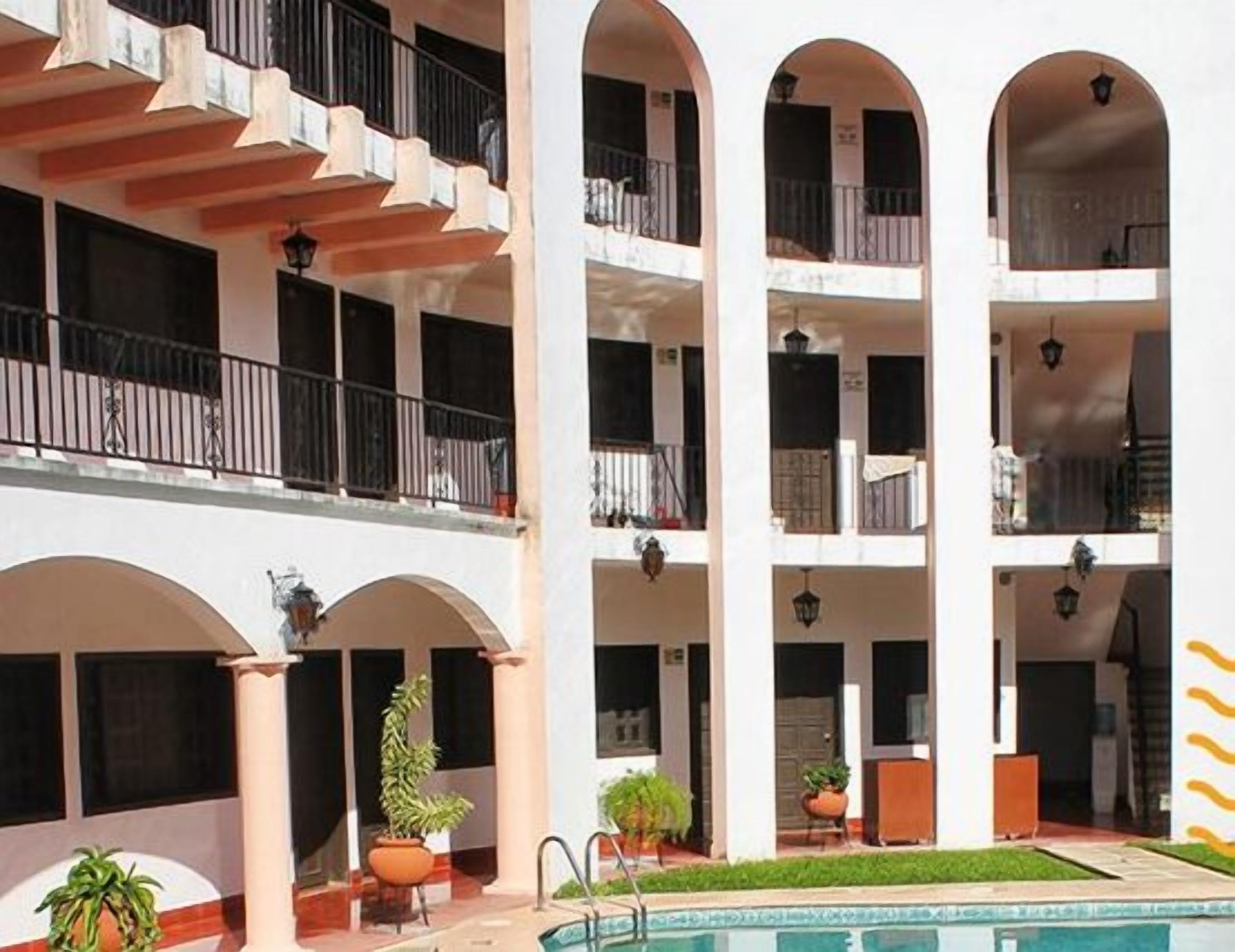A multi-story building with balconies, a swimming pool, and potted plants.