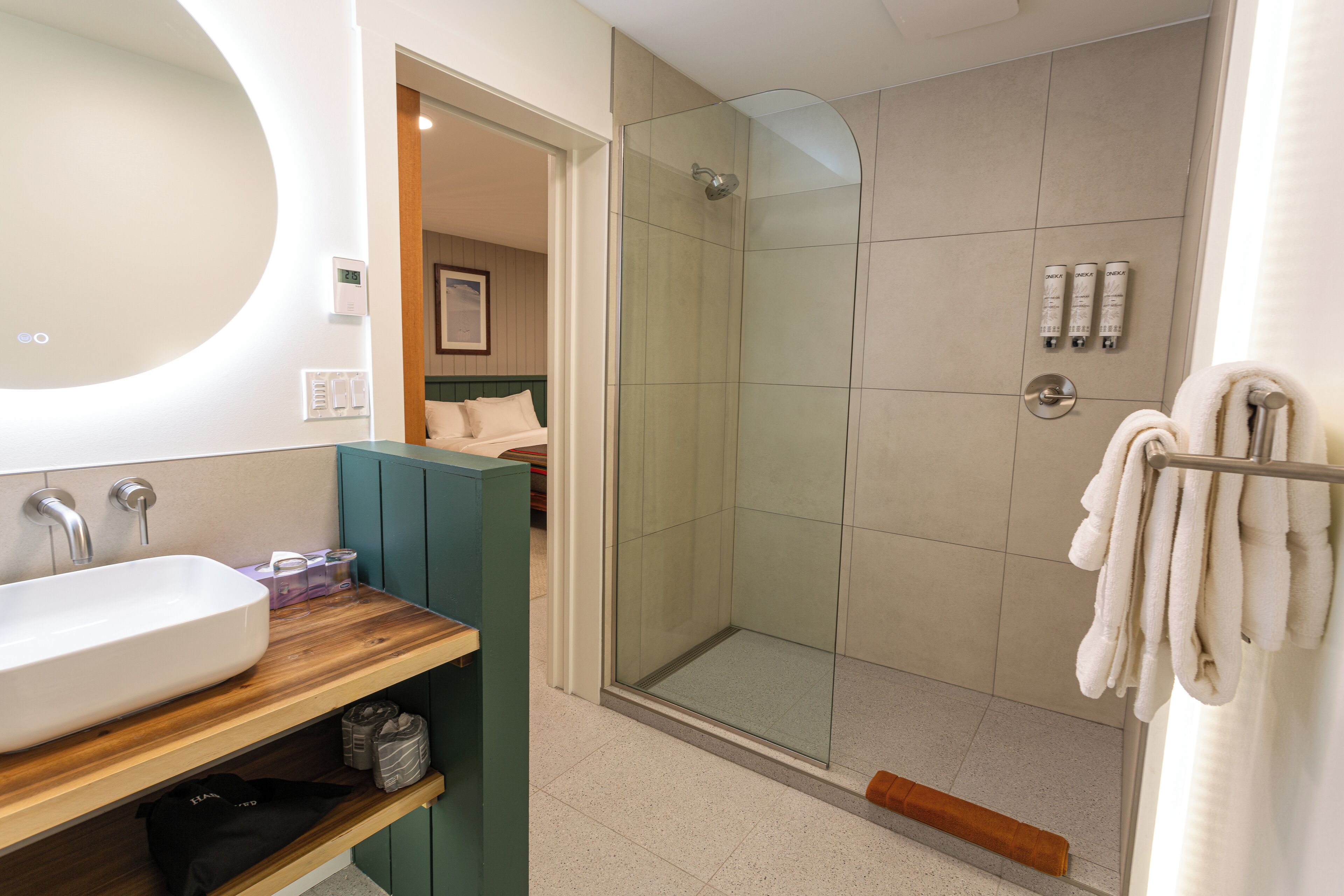 A modern bathroom with a large sink, a glass-enclosed shower, and a towel rack.