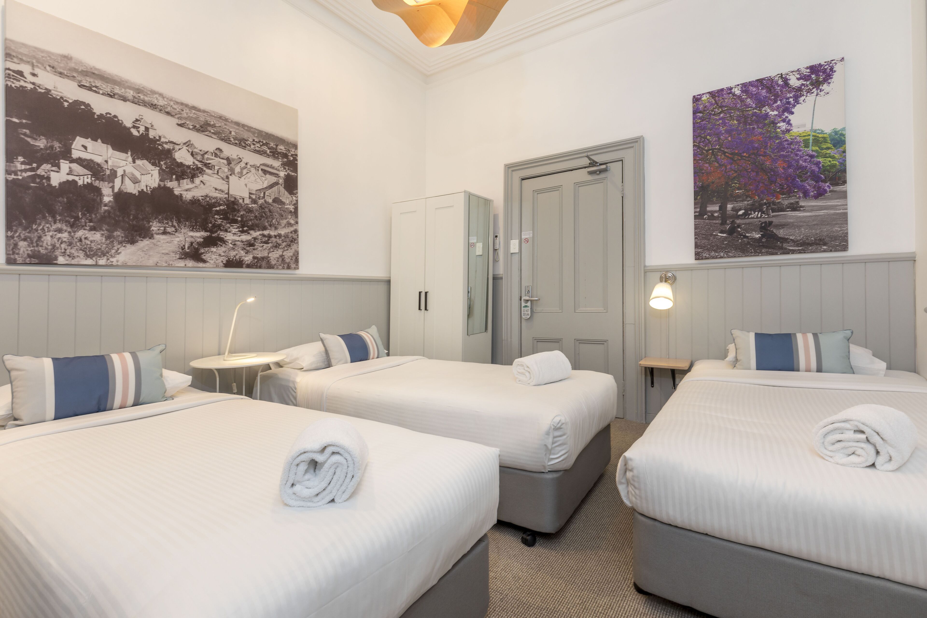 Hotellihuone, jossa on kaksi sänkyä, vaatekaappi, työpöytä ja yöpöytä.