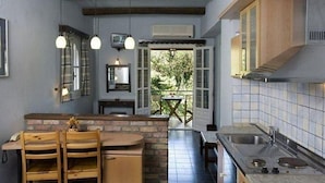 Una cocina con una isla de ladrillo, sillas de madera, una mesa de comedor y vistas al exterior.