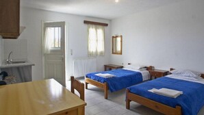 Una habitación con dos camas de madera, una mesa de madera, un lavamanos y un espejo.