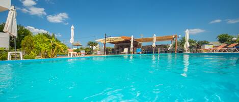 Una piscina al aire libre, sombrillas, tumbonas