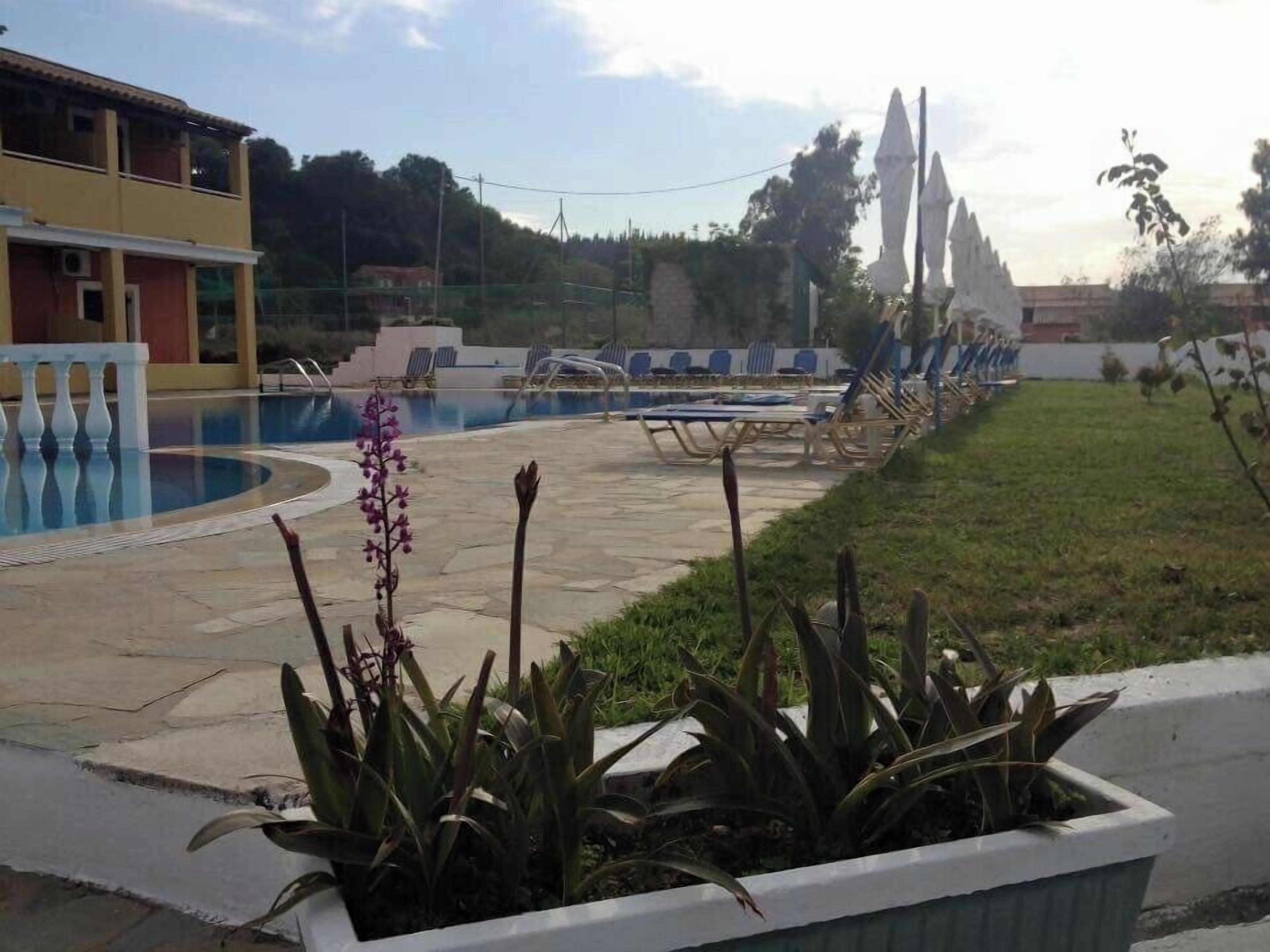 Un'area piscina con lettini e un edificio sullo sfondo.