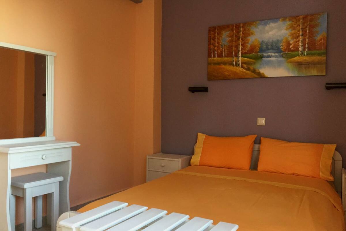 A bedroom with a bed, a nightstand, a dresser, and a painting of a landscape.