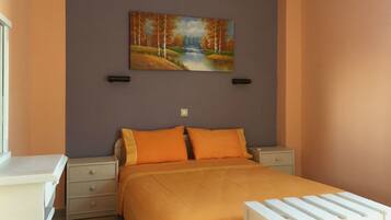 Un dormitorio con una cama, dos mesitas de noche, un aparador y un cuadro de un paisaje en la pared.