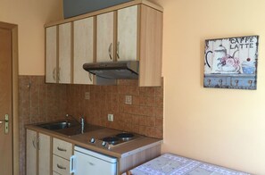 A compact kitchen with wooden cabinets, a gas stove, and a single sink. - Eleni Studios (Kefalonia)