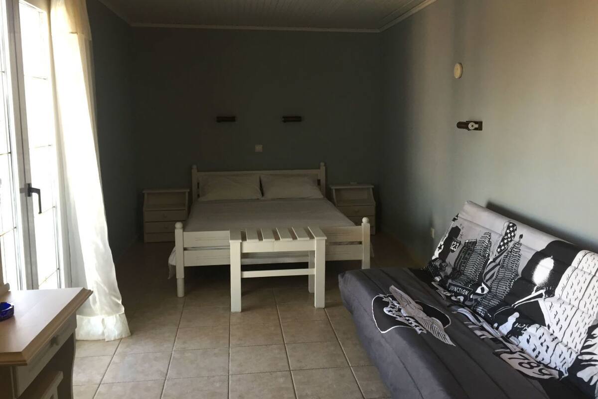 A bedroom with a bed, bedside tables, a bench, and a sofa.