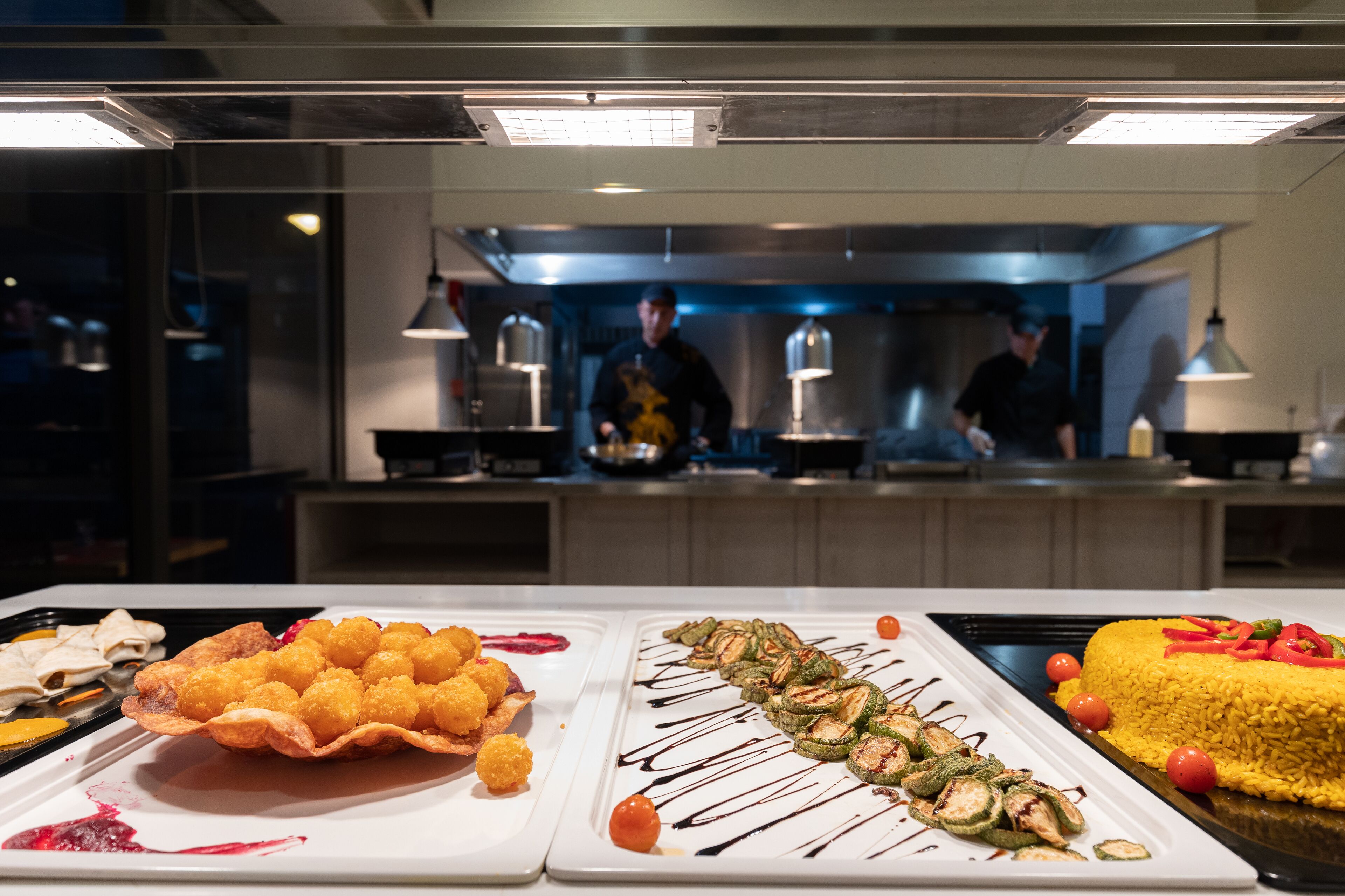 A buffet with various dishes, including a large yellow rice cake, a dish with vegetables, and a dessert.