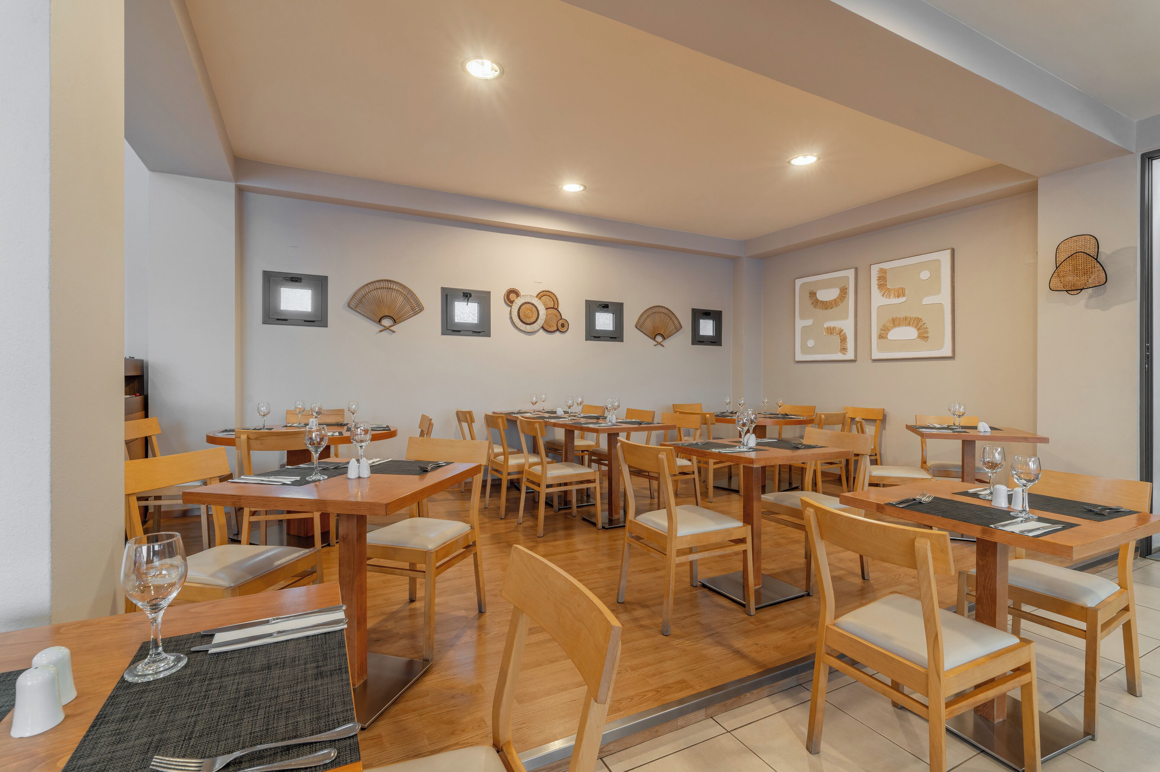 A dining area with multiple tables and chairs, equipped with place settings and wine glasses.