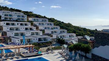 Un resort con piscina, lettini prendisole e moderni edifici bianchi con balconi.