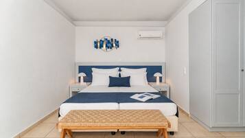A modern bedroom with a bed, bedside tables, a bench, and a wall-mounted air conditioner.